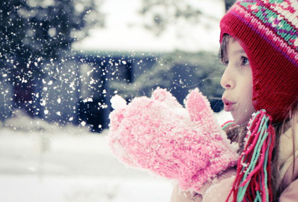 Девочка дует на снег в ладошках